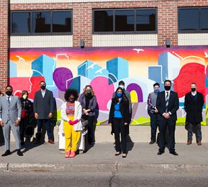 A group of people wearing masks in front of the mural outside BMO’s Lake Street branch in Minneapolis