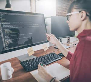 A woman reviews programming code on her computer