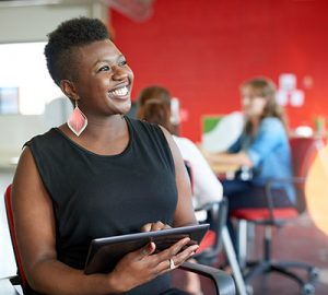 A woman of color holding a tablet and smiling