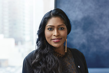 A BMO Employee, Asia Shahulhameed, stands by a window smiling