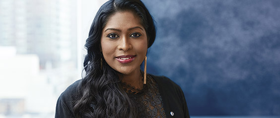 A BMO Employee, Asia Shahulhameed, stands by a window smiling
