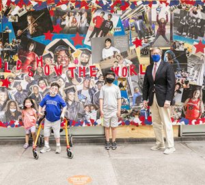 Dave Casper stands in front of the mural with three school children