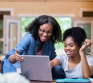 A mother and daughter looking at a laptop