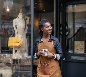 A shop owner standing outside a storefront door
