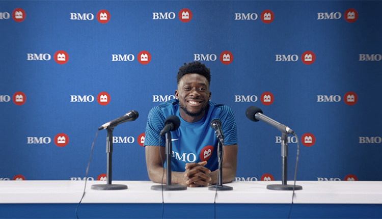 Alphonso Davies at a press conference with BMO logos in the background